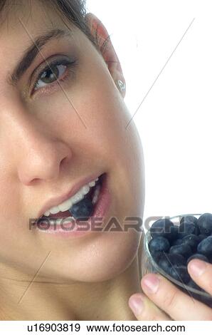 Stock Photo - Woman, Brown Hair, Beauty, White undershit, Eating, Fruit, Blueberry. Fotosearch