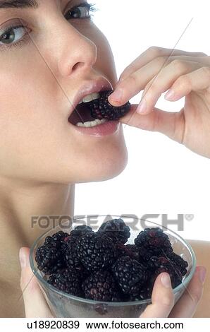 Stock Photo - Woman, Brown Hair, Beauty, White undershit, Eating, Fruit, Mulberry. Fotosearch