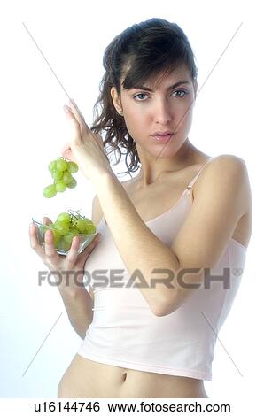 Stock Photograph - Woman, Brown Hair, Beauty, White undershit, Eating, Fruit, Grapes. Fotosearch