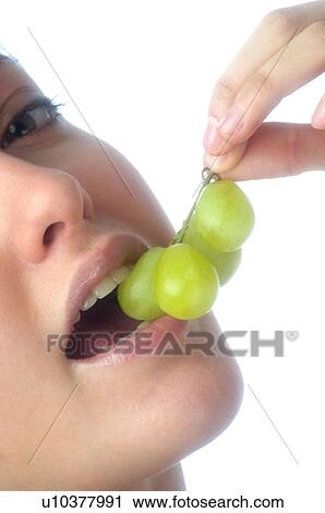 Stock Image - Woman, Brown Hair, Ponytail, Beauty, White undershit, Eating, Fruit. Fotosearch
