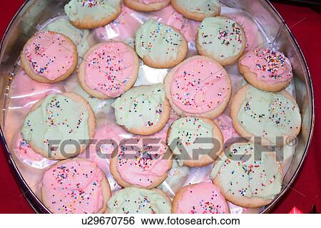 Stock Photograph - Tin of pastel pink and lime green frosted sugar cookies with sprinkles. Fotosearch