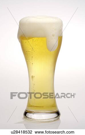 Stock Image - Glass of beer, froth overflowing out of the glass. Fotosearch
