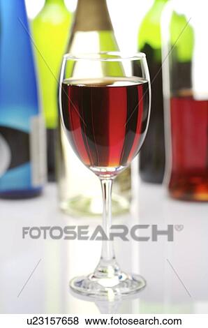 Glass of red wine in front of several wine bottles View Large Photo Image Stock Photo - Glass of red wine in front of several wine bottles. Fotosearch