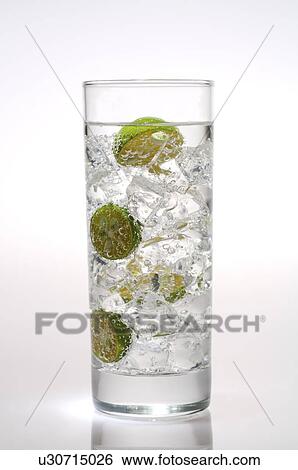 Stock Photograph - Glass of water filled with ice cubes and kumquat. Fotosearch