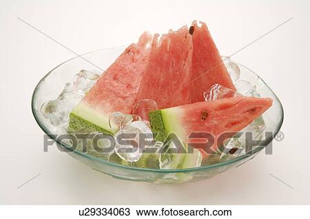 Stock Image - Slices of watermelon in a shallow glass bowl with ice cubes. Fotosearch