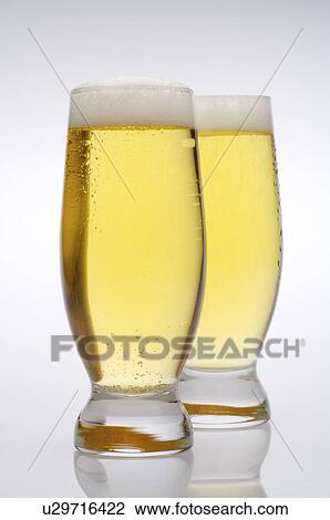 Stock Image - Two glasses of beer, with froth on top. Fotosearch
