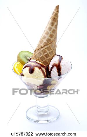 Stock Image - Two scoops of ice cream and an ice cream cone in a glass, with fruit garnish. Fotosearch