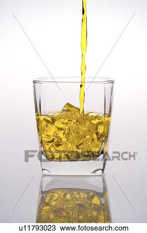 Whiskey being poured into a glass with ice cubes View Large Photo Image Stock Image - Whiskey being poured into a glass with ice cubes. Fotosearch