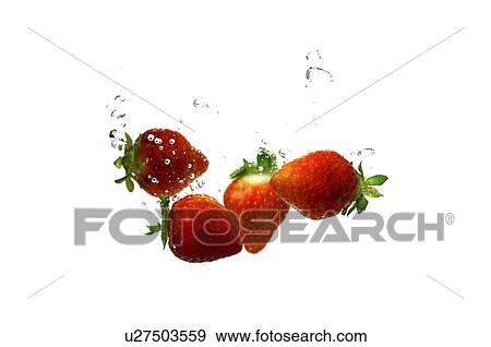 Stock Photo - Fresh red strawberries in water, creating bubbles. Fotosearch