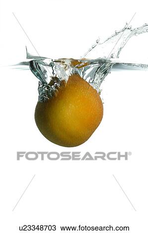 Stock Image - Pear falling into water, splashing water upwards. Fotosearch