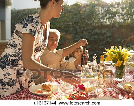 Picture - Family at dinner table in garden. Fotosearch