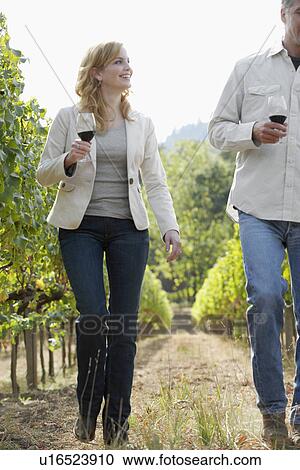 Stock Image - Man and woman walking in vineyard, Napa Valley, California, USA. Fotosearch