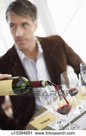 Stock Image - Man tasting red wine (focus on foreground, tilting). Fotosearch