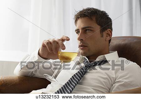 Mid adult businessman drinking white wine on armchair View Large Photo Image Stock Image - Mid adult businessman drinking white wine on armchair. Fotosearch