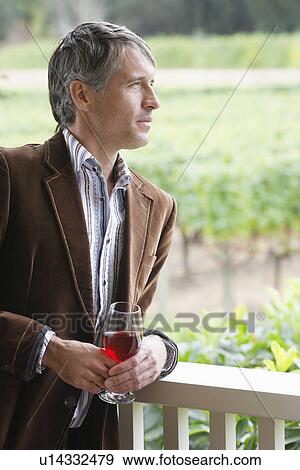 Mid adult man drinking red wine on patio (portrait) View Large Photo Image Stock Photo - Mid adult man drinking red wine on patio (portrait). Fotosearch