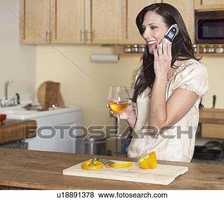 Stock Photo - Mid-Adult Woman on Phone While Cooking. Fotosearch