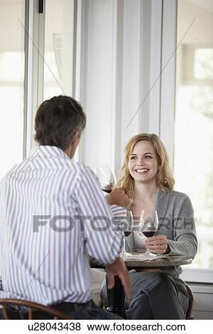 Stock Photo - Woman and man tasting red wine (focus on background). Fotosearch