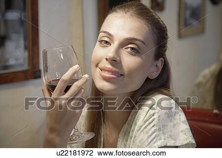 Stock Image - Young woman drinking red wine (portrait). Fotosearch