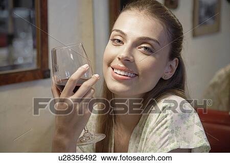 Stock Image - Young woman drinking red wine (portrait). Fotosearch
