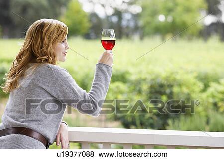 Stock Photo - Young woman holding glass of red wine. Fotosearch