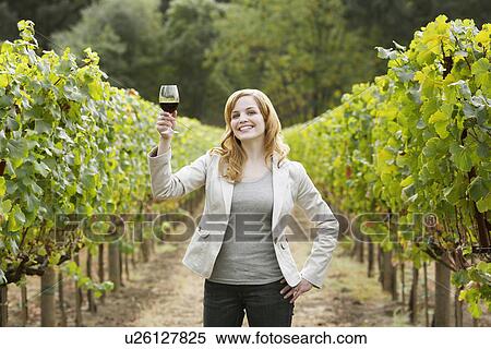 Young woman holding glass of red wine in vineyard (portrait) View Large Photo Image Stock Photography - Young woman holding glass of red wine in vineyard (portrait). Fotosearch