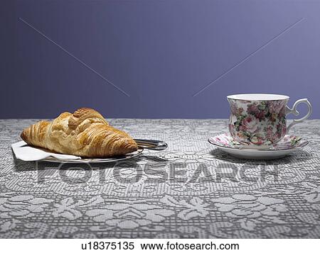 Stock Photography - Tea cup and croissant on table. Fotosearch
