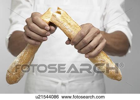 Stock Photograph - Chef breaking baguette (mid section). Fotosearch