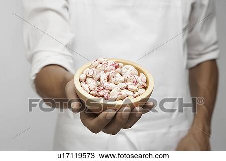 Stock Image - Chef holding bowl of borlotto beans (mid section). Fotosearch