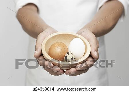 Picture - Chef holding bowl of eggs (mid section). Fotosearch