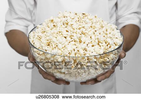 Stock Photo - Chef holding bowl of popcorn (mid section). Fotosearch