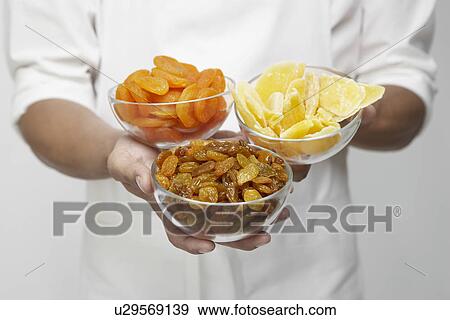 Chef holding bowls of dried fruits (mid section) View Large Photo Image Stock Photo - Chef holding bowls of dried fruits (mid section). Fotosearch