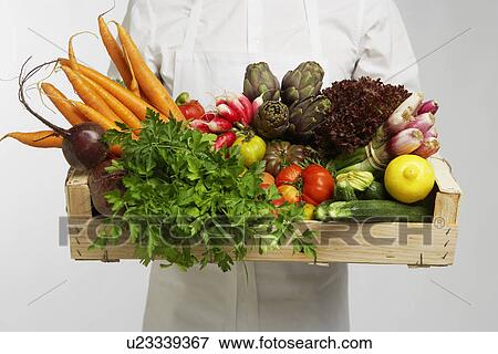 Stock Photo - Chef holding box of vegetables (mid section). Fotosearch
