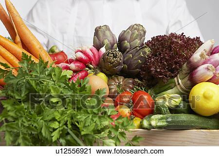Stock Image - Chef holding box of vegetables (close-up). Fotosearch