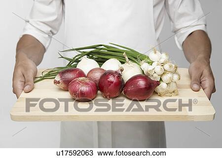 Stock Image - Chef holding cutting board with onions. Fotosearch