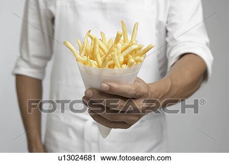 Stock Image - Chef holding french fries (mid section). Fotosearch