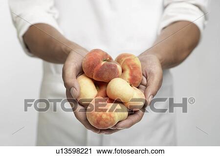 Stock Image - Chef holding peaches (mid section). Fotosearch