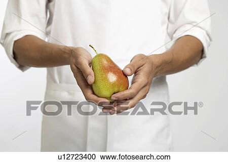 Stock Image - Chef holding pear (mid section). Fotosearch