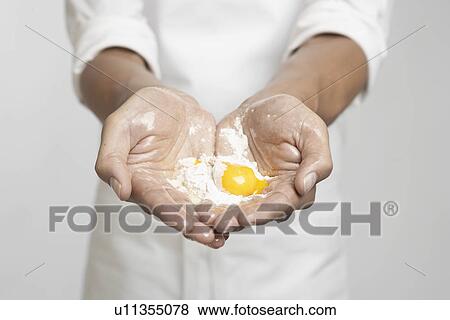 Stock Photo - Egg yolk and flour in chef's hands (close-up). Fotosearch