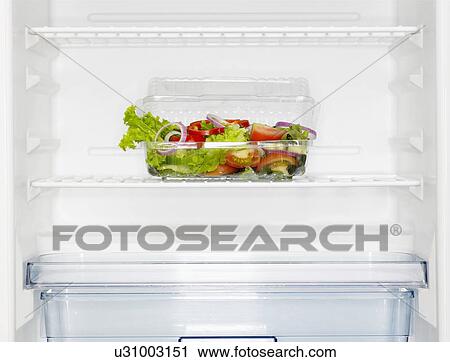 Stock Image - Salad box in fridge (close-up). Fotosearch