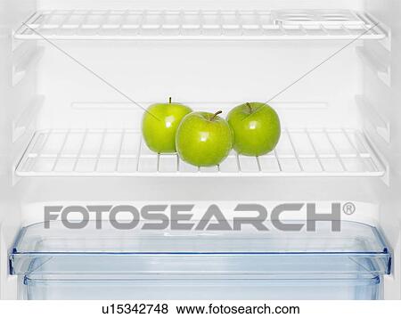 Stock Photo - Three green apples in fridge (close-up). Fotosearch
