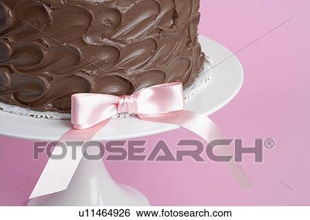 Stock Photograph - Pink ribbon bow on chocolate cake (close-up). Fotosearch
