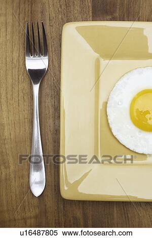 Fork beside fried egg on plate View Large Photo Image Stock Photography - Fork beside fried egg on plate. Fotosearch