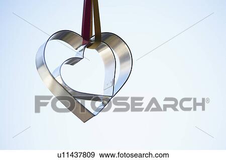 Stock Photo - Two heart shaped cookie cutters hanging (close-up). Fotosearch