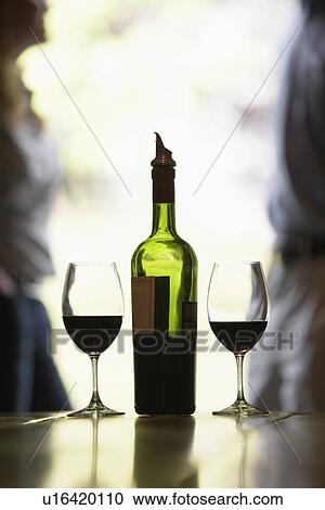 Wine bottle and glasses, couple in background (focus on foreground) View Large Photo Image Stock Image - Wine bottle and glasses, couple in background (focus on foreground). Fotosearch