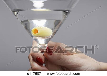 Stock Image - Woman's hand holding martini cocktail (close-up). Fotosearch