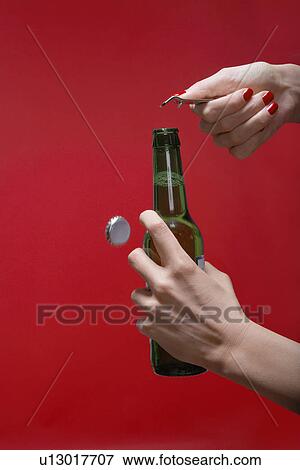 Stock Photo - Young woman's hands opening bottle of beer (close-up). Fotosearch