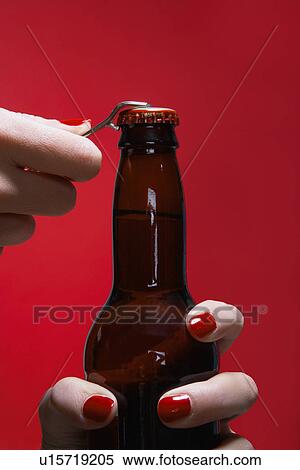 Stock Photography - Young woman's hands opening bottle of beer (close-up). Fotosearch
