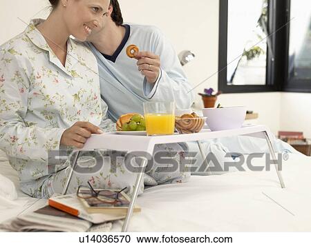 Couple having breakfast on bed, husband whispering to wife View Large Photo Image Stock Image - Couple having breakfast on bed, husband whispering to wife. Fotosearch