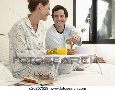 Husband and wife having breakfast on bed View Large Photo Image Stock Photo - Husband and wife having breakfast on bed. Fotosearch