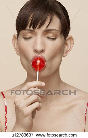 Stock Photo - Mid adult woman eating lollipop. Fotosearch